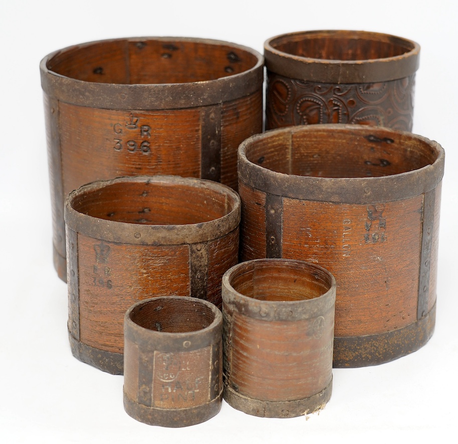 A matched set of five early 20th century iron bound bushel measures, one peck to half pint, together with a pressed card paper basket. Condition - fair to good